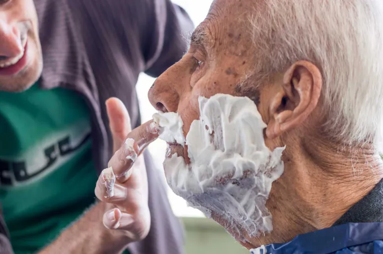 Younger man helping an older man shave