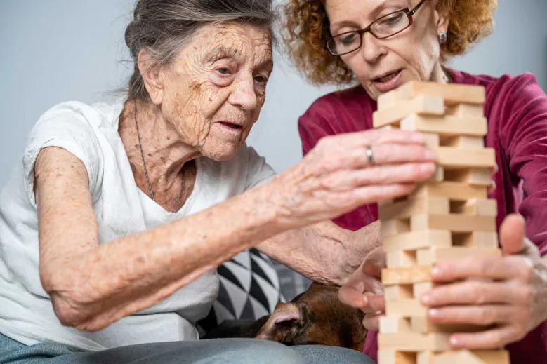 Older woman playing a block-stacking game with a younger woman