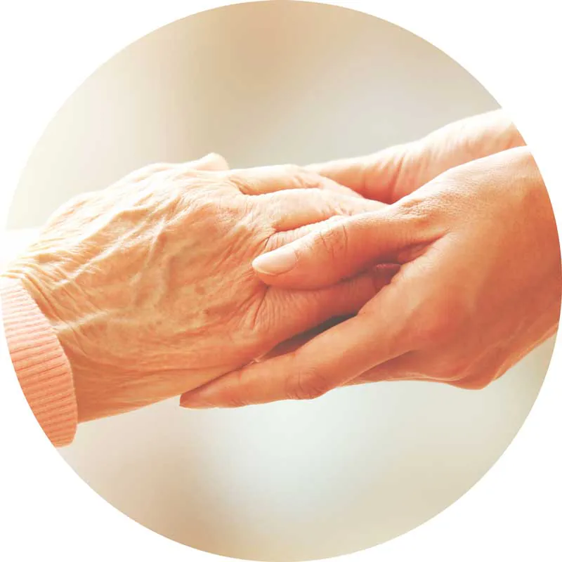 Younger person's hands holding an older person's hand